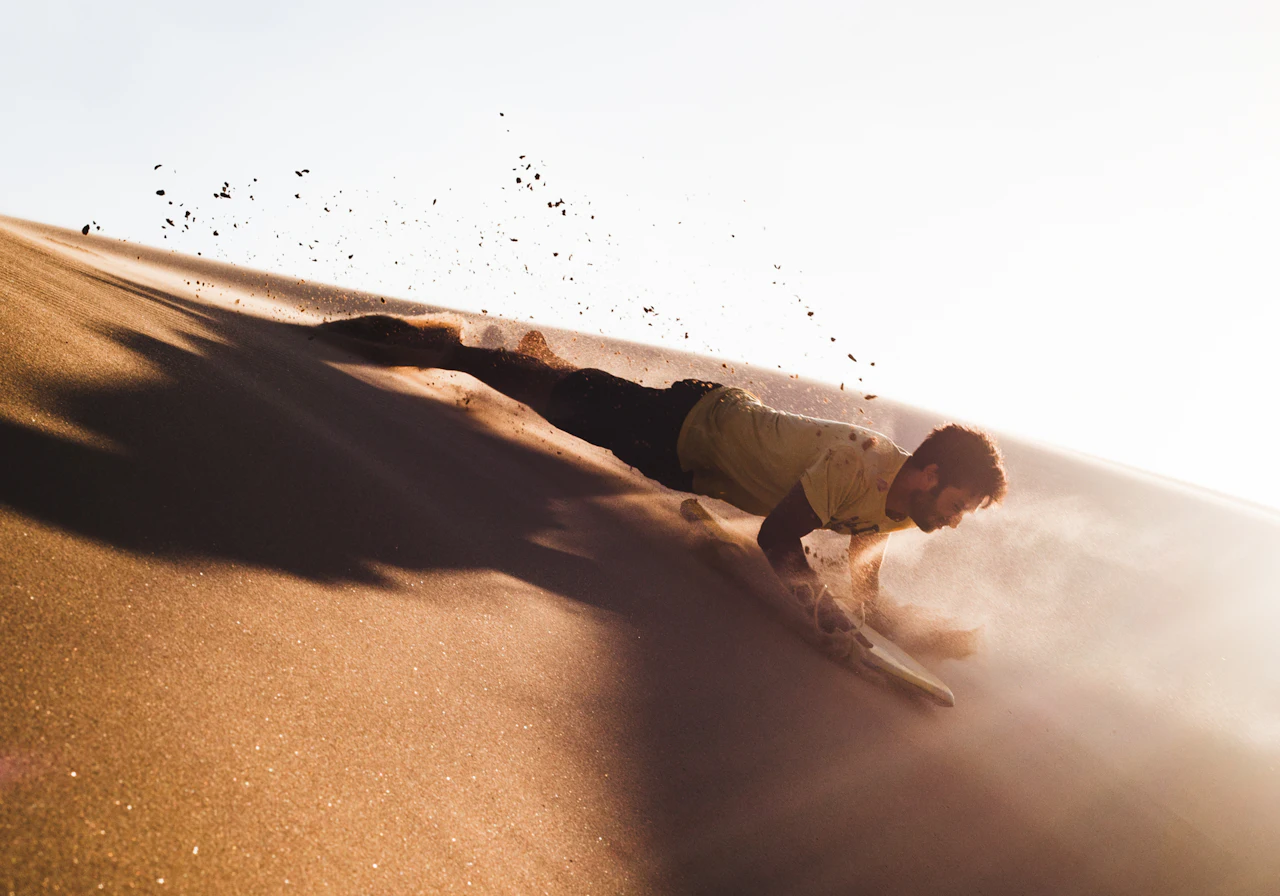 Illustrative sandboarding descent on a sand dune