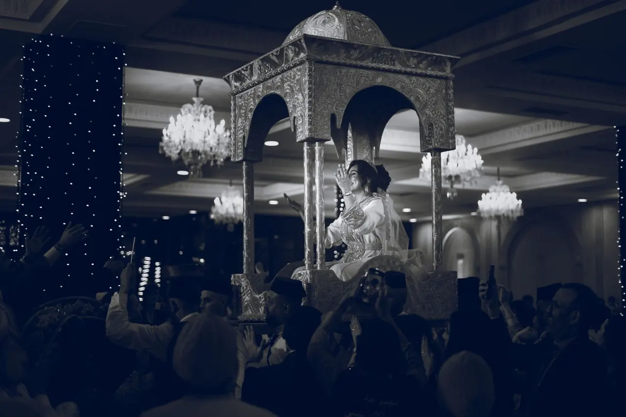 A bride carried in an ornate amariya at a Moroccan wedding celebration
